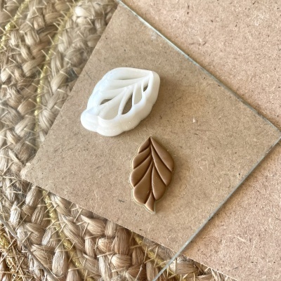 Duas formas de silicone em formato de folha em cima de vidro sobre cortiça e tapete de fibras naturais