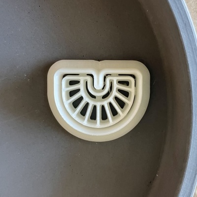 Prato cinza com grelha branca semi-circular de plástico no centro