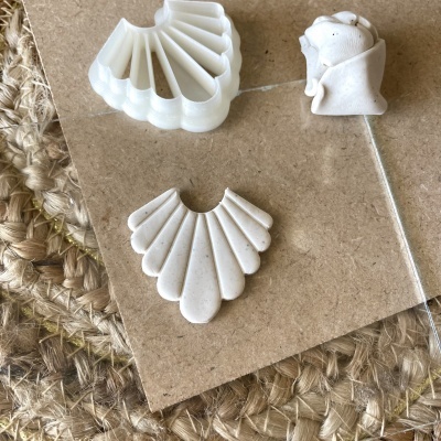 Moldes ou acessórios brancos em forma de concha sobre madeira e tecido trançado rústico