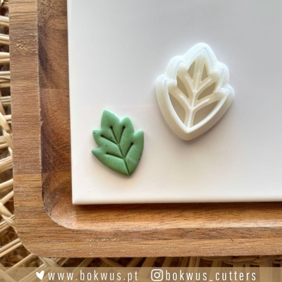 Cortador de bolacha branco em forma de folha com massa verde modelada ao lado