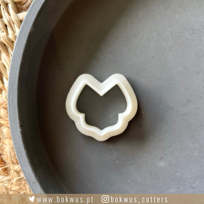 Forma de cortar biscoitos de plástico branco em fundo cinza escuro com superfície de ráfia.