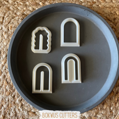 Quatro cortadores de massa geométricos brancos em prato cinzento com etiqueta BOKWUS CUTTERS.