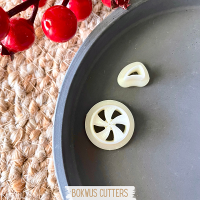 Dois cortadores de massa brancos em prato cinzento com bagas vermelhas e fundo de corda.