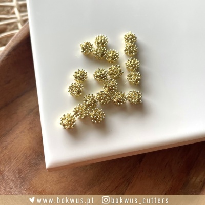 Botões dourados texturizados sobre superfície branca em mesa de madeira