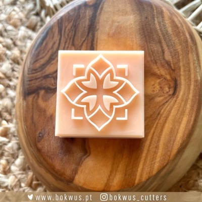 Saboneteira quadrada cor pêssego com desenho branco sobre base redonda de madeira