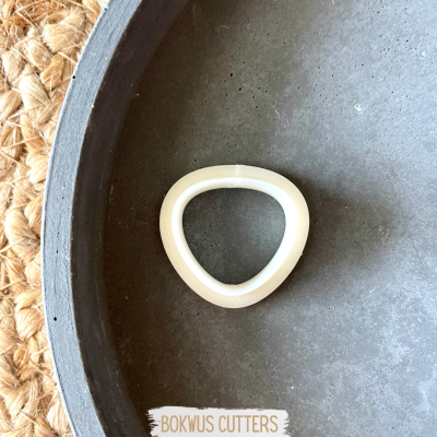 Cortador triangular de plástico branco sobre superfície cinzenta com etiqueta BOKWUS CUTTERS