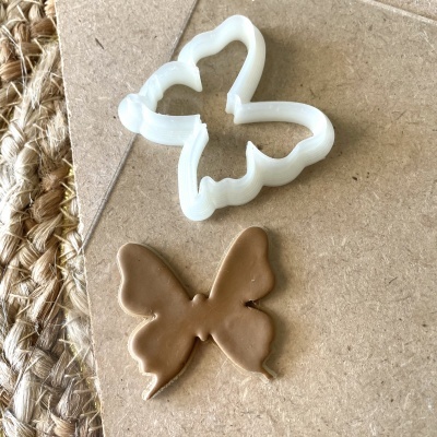 Forma de biscoito branca em plástico e massa castanha moldada na forma de borboleta