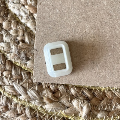 Presilha de plástico branco sobre cartão castanho em tapete de fibras trançadas