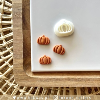 Três cortantes pequenos em forma de abóbora em placa branca sobre madeira clara e fundo trançado