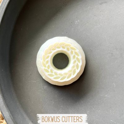 Forma de corte circular branca com padrão de folhas em superfície preta