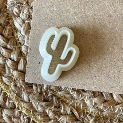 Clip branco em forma de cacto sobre cartão e tapete tecido castanho