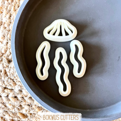 Conjunto de cortadores de massa em silicone branco com quatro formas diferentes sobre uma travessa preta.