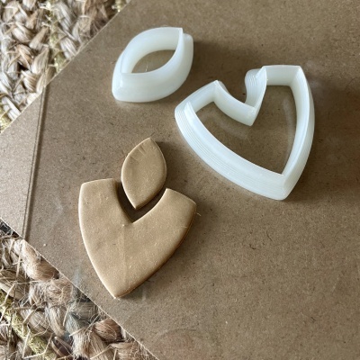 Cortadores de massa brancos e figura cortada em massa marrom clara sobre madeira