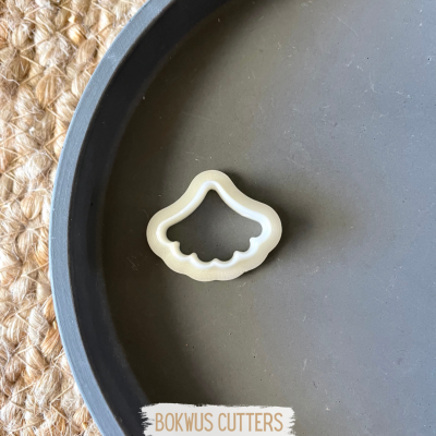 Cortador de biscoitos branco em prato cinzento sobre tecido trançado