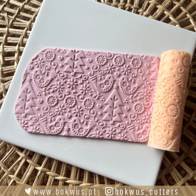 Rolo de silicone com padrão floral e pássaros em relevo sobre placa branca e base de vime