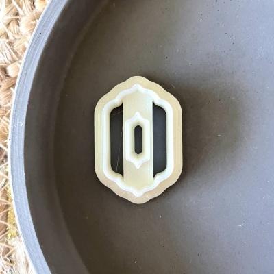 Cortador de bolacha em plástico bege e branco numa superfície cinza