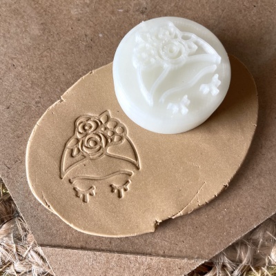 Selo de carimbo branco com padrão floral sobre argila marrom