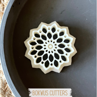 Cortador branco em formato de flor dentro de tigela cinzenta