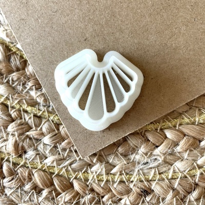 Moldura branca em plástico em forma de concha sobre papel castanho e tapete trançado