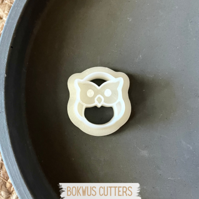 Cortador de bolachas branco em forma de coruja sobre prato escuro