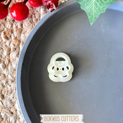 Cortador de biscoitos em forma de Papai Noel branco sobre prato cinza com decoração festiva