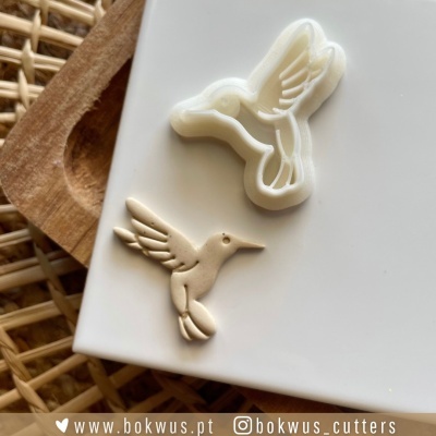 Forma de cortar e peça de pasta polimérica em formato de beija-flor sobre prato branco