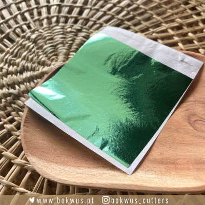 Bloco de capa verde metálico num prato de madeira sobre tapete de fibras naturais