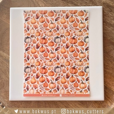 Cartaz com padrão de abóboras laranja e bege sobre placa branca em mesa de madeira