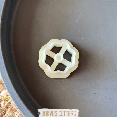 Cortador de plástico branco em forma de flor dentro de tigela cinza