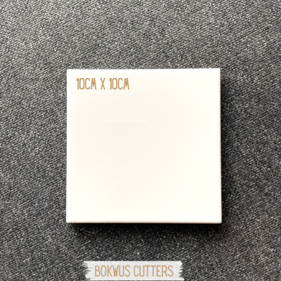 Peça quadrada branca de cerâmica 10x10 cm sobre tecido cinza