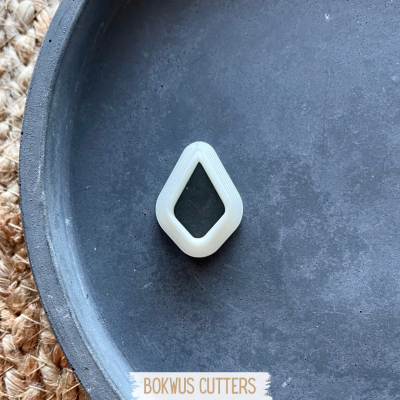 Cortante de plástico branco em forma de losango sobre prato cinzento