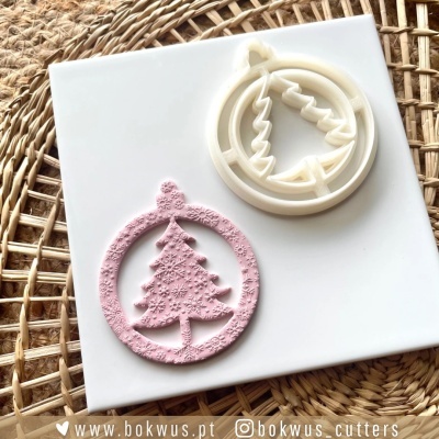 Cortador de massa branco e molde texturizado rosa de árvore de Natal sobre base cerâmica e suporte de palha