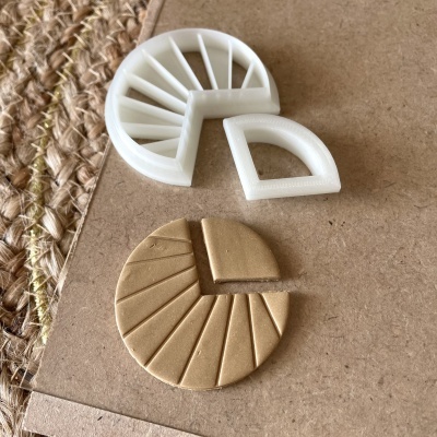 Molde branco de plástico e peça de argila dourada em forma de círculo dividido em fatias sobre cartão castanho