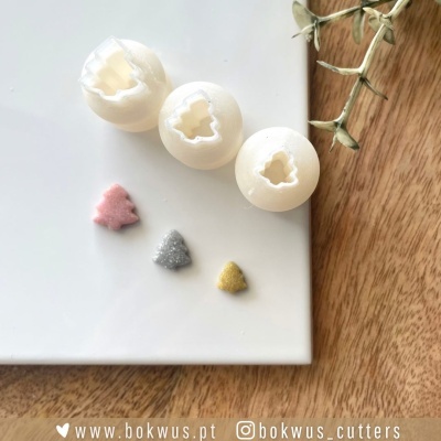 Três cortadores brancos de árvore de Natal com recortes coloridos em placa branca