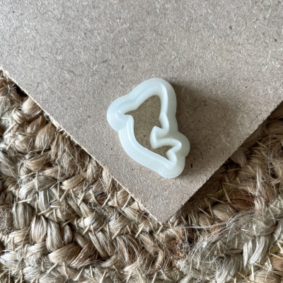 Corta-massa branco em forma de sino sobre tecido rústico e cartão seco