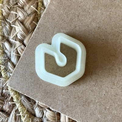 Objeto plástico branco em forma geométrica sobre cartão castanho em tecido de juta