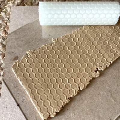 Rolo branco com padrão de colmeia e placa castanha com textura idêntica sobre superfícies castanhas