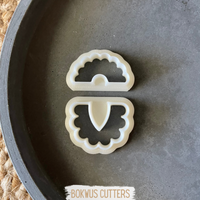 Dois cortadores de massa ou biscoitos brancos em superfície cinzenta redonda