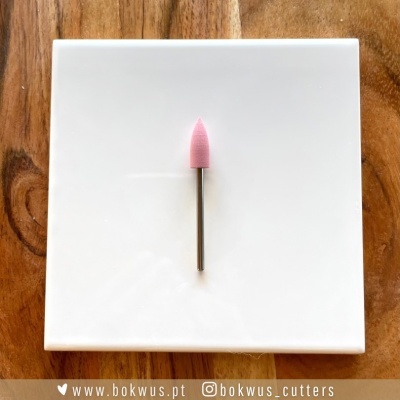 Broca de acabamento rosa e metal sobre prato branco e fundo de madeira