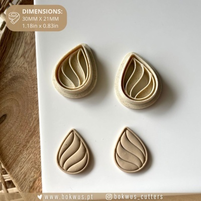 Conjunto de quatro cortadores em forma de gota cor bege clara com padrão ondulado em fundo branco e madeira.