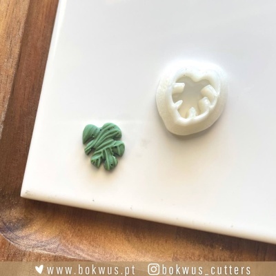 Cortador de plastico branco com forma de folha e peça verde cortada em forma de folha