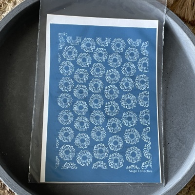 folha azul com padrões brancos de flores dentro de embalagem plástica em superfície redonda cinzenta