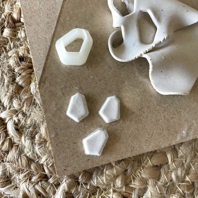 Peças de cerâmica brancas geométricas sobre madeira e tecido trançado