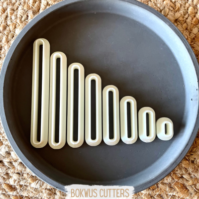 Conjunto de cortadores de massa retangulares em travessa cinzenta sobre palha