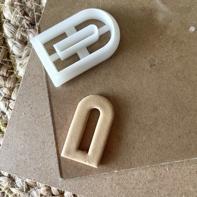 Duas fivelas em forma de D, uma branca e outra bege, sobre madeira clara e tapete de fibras naturais