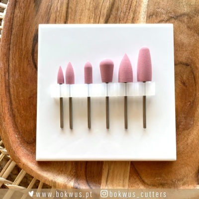 Conjunto de pontas abrasivas rosa em suporte branco numa mesa de madeira