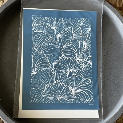 Papel com padrão branco de folhas sobre fundo azul dentro de saco plástico numa tigela cinzenta