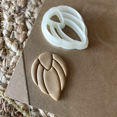 Cortador de biscoitos branco em formato de flor e massa crua de biscoito na mesa