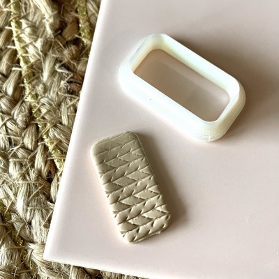 duas peças retangulares, uma bege texturizada e outra branca oca, sobre superfície rosa e tapete natural