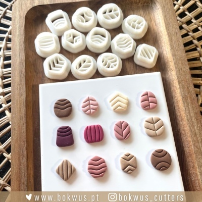 Cortantes e peças de pasta polimérica com padrões geométricos e de folhas em bandeja de madeira e placa branca